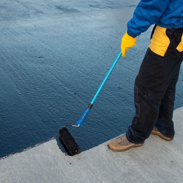 Worker applies bitumen mastic on the foundation